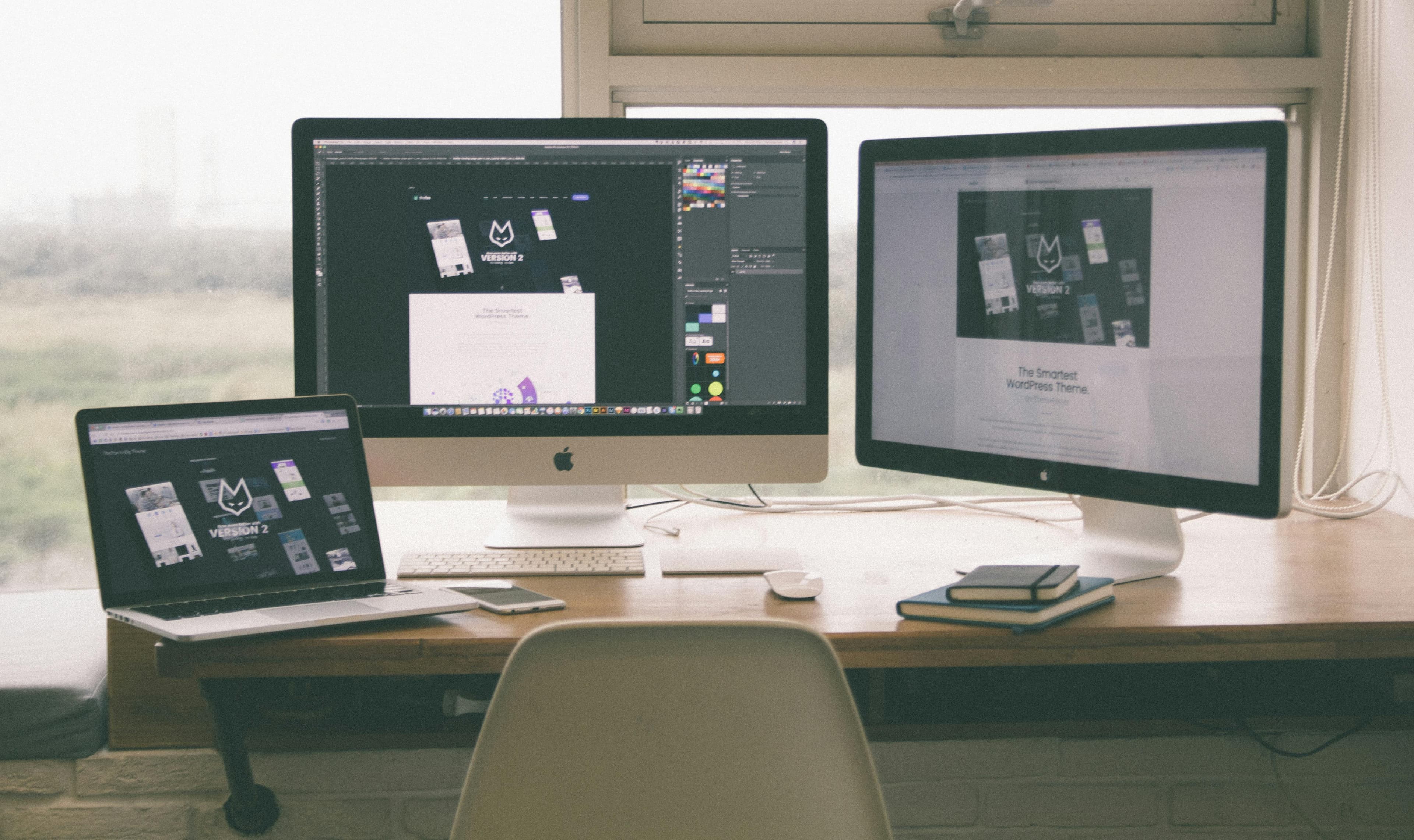 Two computer screens with a laptop, notepad, keyboard, mouse and a digital drawing device.