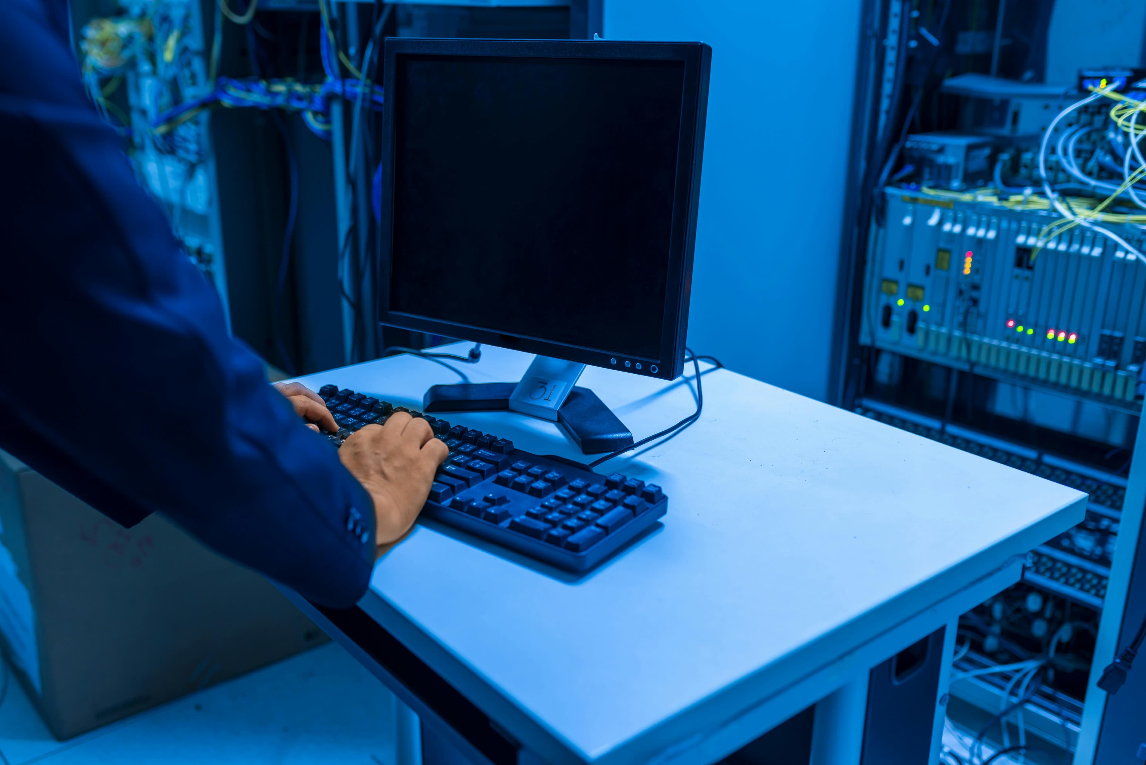Person in a blue tinted room typing on a laptop
