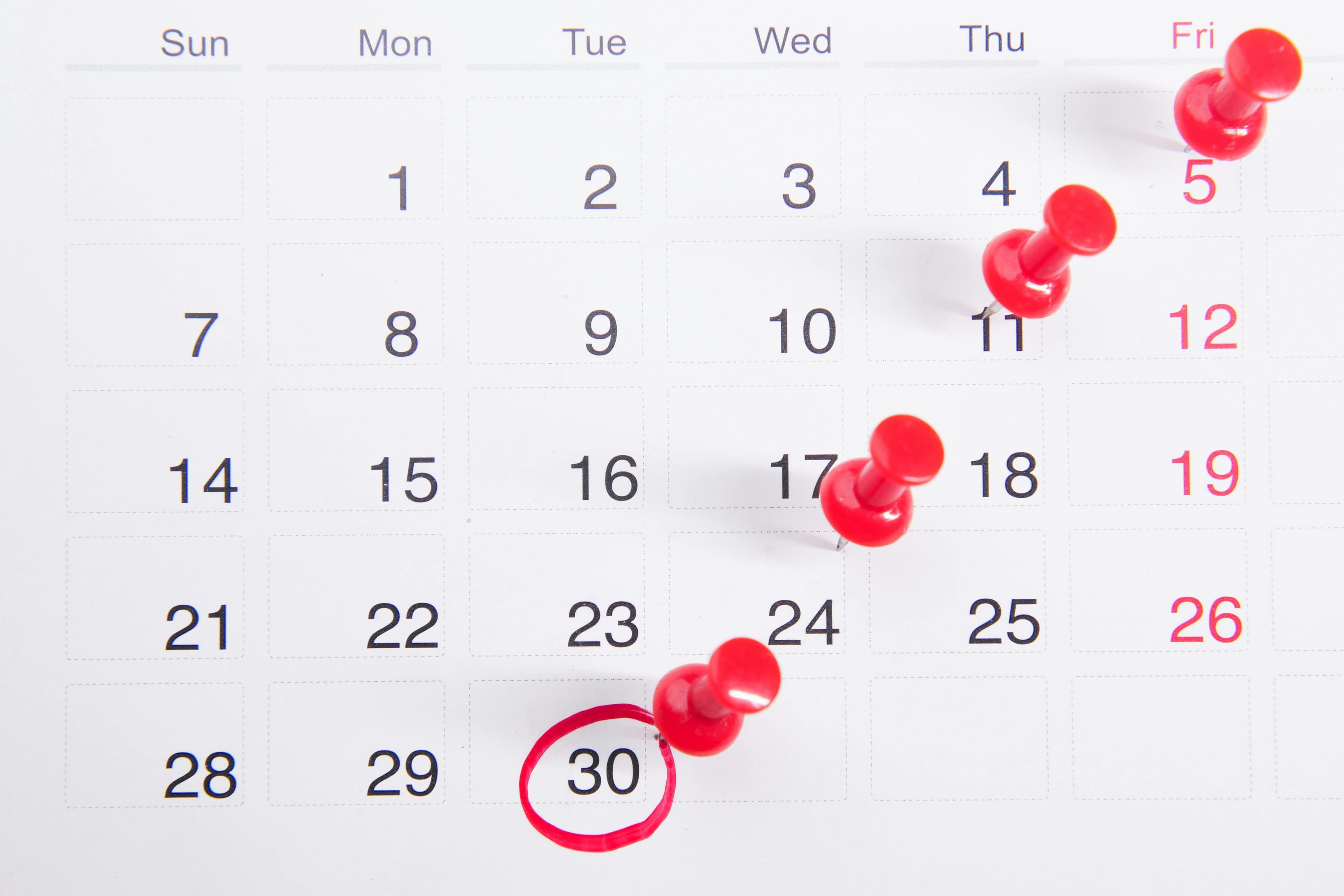 Calendar with red pins marking various dates and the 30th date circled